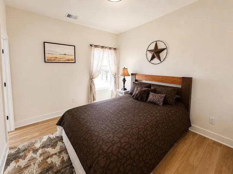 Well-appointed bedroom with a large bed, nightstand lighting, and a window with curtains for natural light.