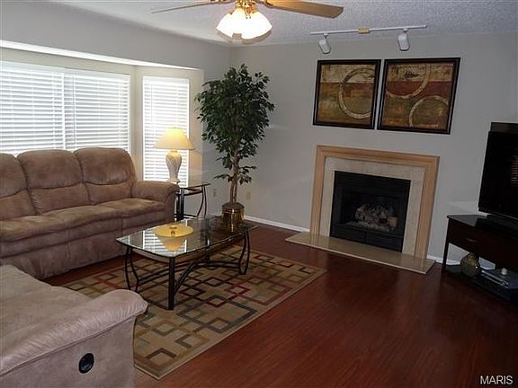 Great room with bay window, ceiling fan, wide plank laminate wood flooring & gas fireplace.