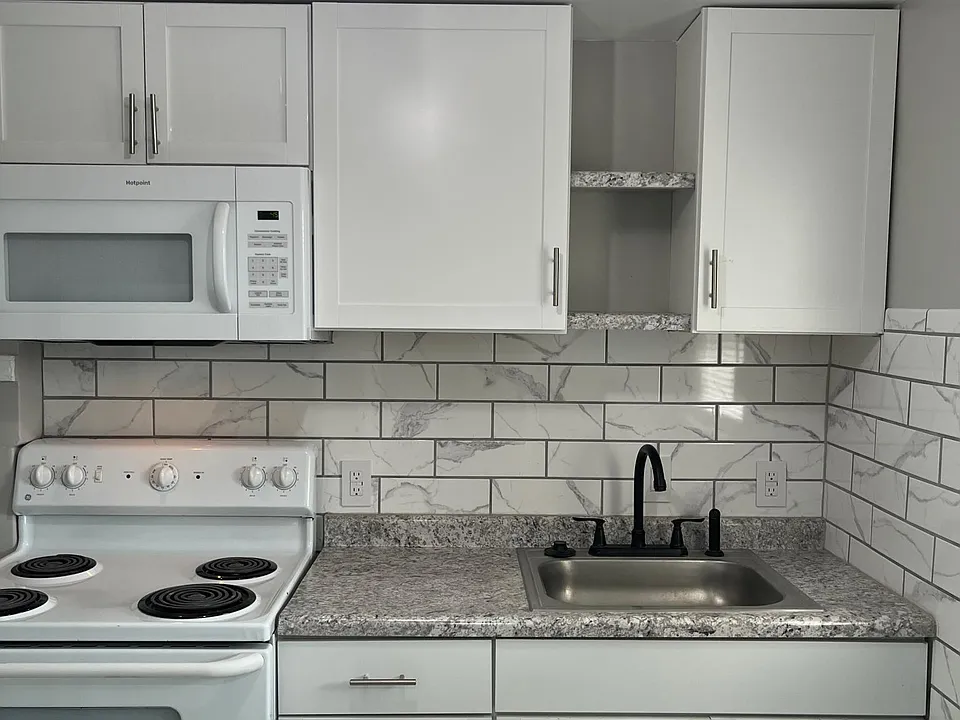 remodeled kitchen new cabinets, microwave, air vent, garbage disposal, flooring with matching backsplash