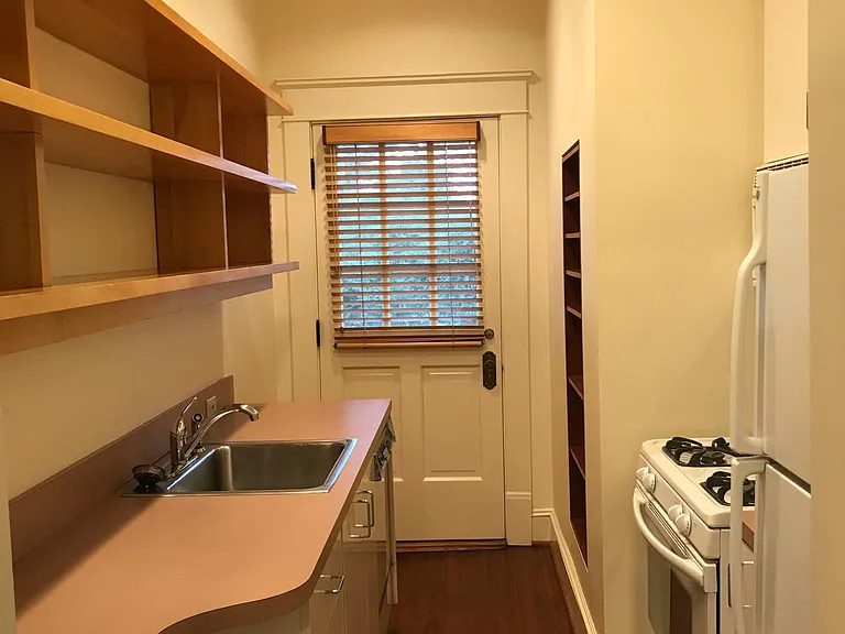 Kitchen with back entry door; open maple shelves above sink counter; dishwasher below