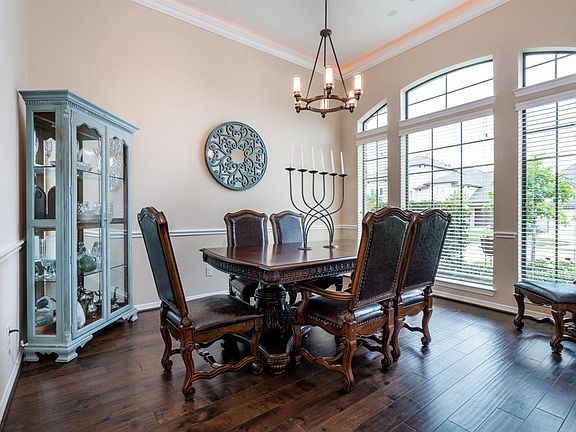 Spacious dining room lit by large windows and framed by crown molding with lighting.
