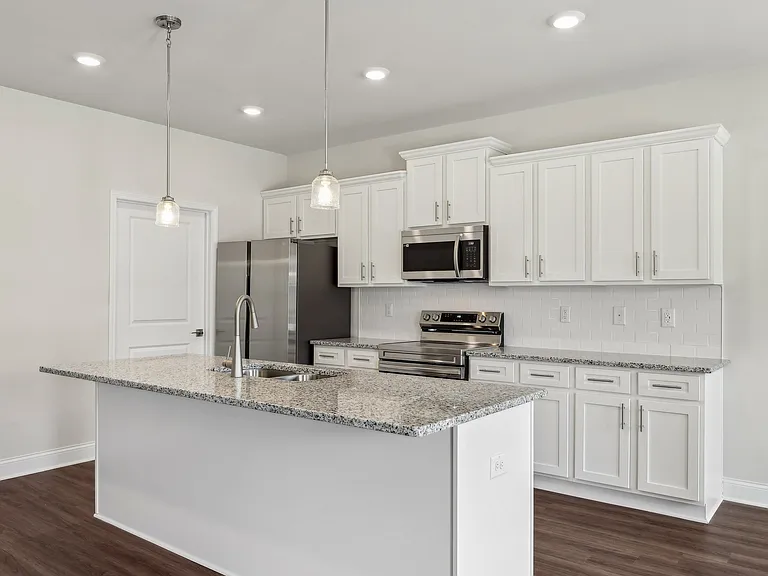 Sleek kitchen with white cabinetry and granite countertops.
