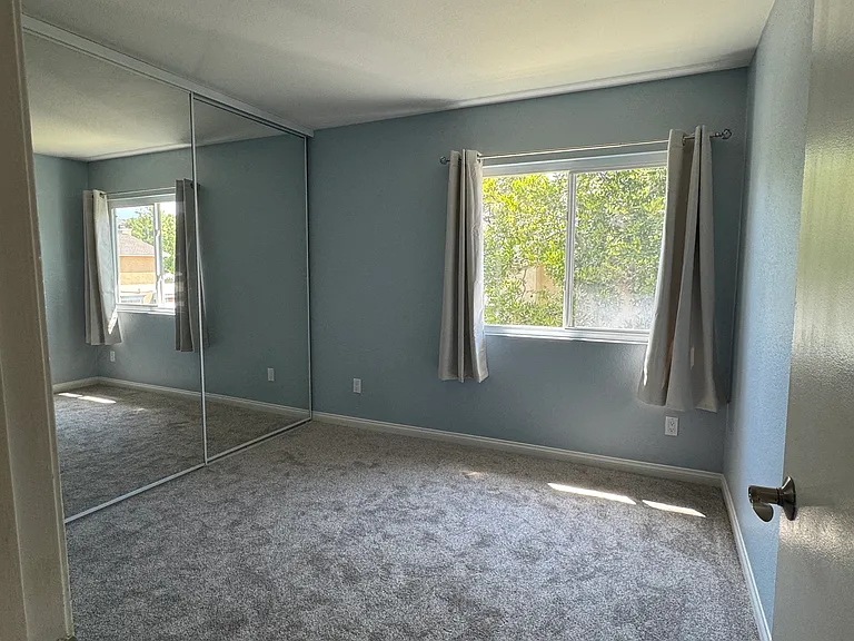 Bright and spacious second bedroom with brand-new carpet and mirrored closet doors