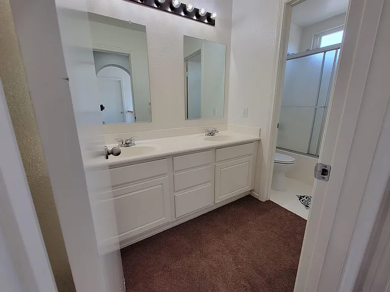 Hall Bathroom with double sink and a door for a private toilet with shower.