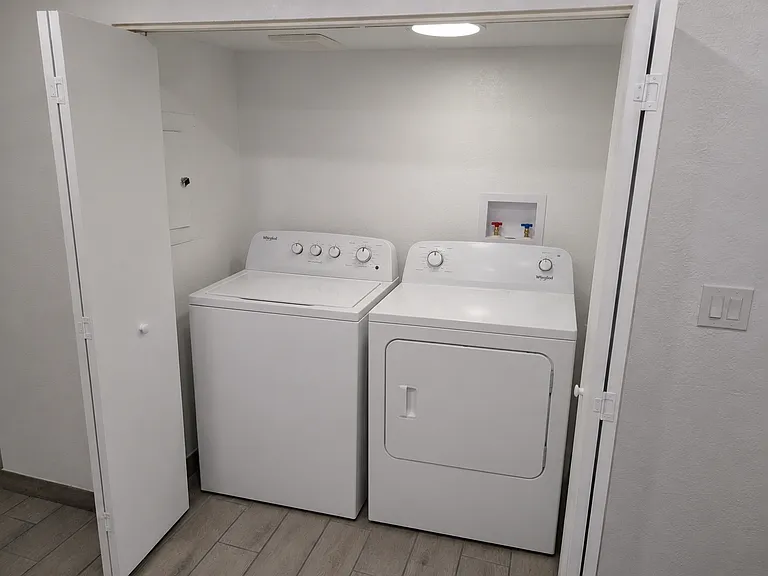 Convenient indoor laundry closet featuring full hookups and a crisp, clean setup. Continuous wood-look tile flooring flows right in. Full-size Whirlpool washer and dryer can be provided upon request if needed!