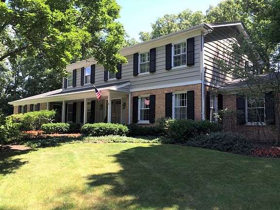 The home is framed in lush foliage and mature trees