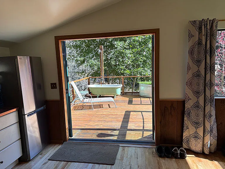 Private deck with clawfoot tub & shower from inside kitchen looking out French doors