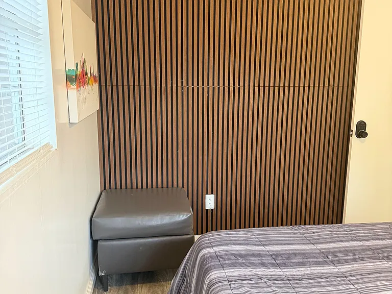 Furnished bedroom with a comfortable bed, window blinds for light control, and durable wood-look flooring.