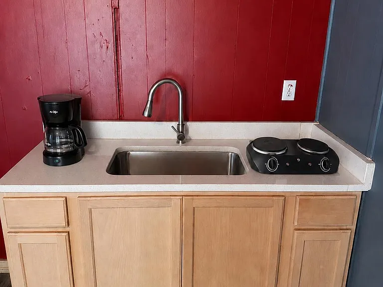 Kitchenette with stainless sink, ample base cabinetry, and counter space with a cooktop and coffee station.