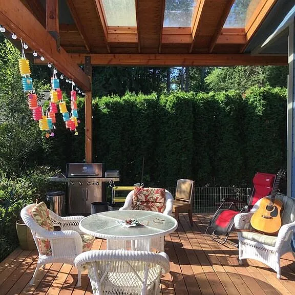 Covered skylight deck gathering space with a gorgeous view of the yard and bay