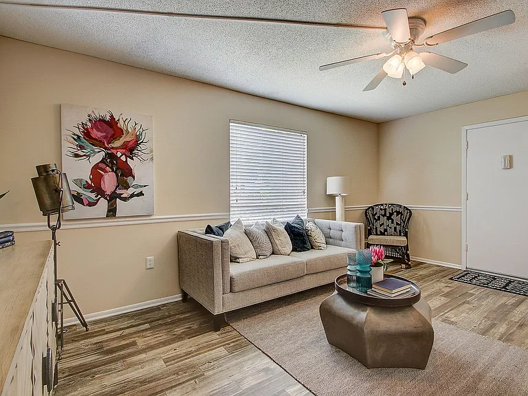 Chic living room with elegant decor, featuring a modern gray sofa adorned with plush cushions, stylish art, and natural light from a large window.