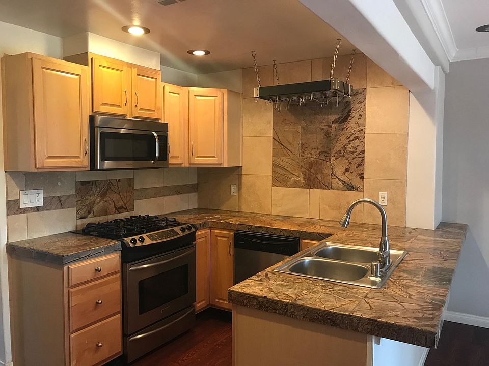 Open kitchen with stainless steel gas cooktop/convection oven, dishwasher and microwave.