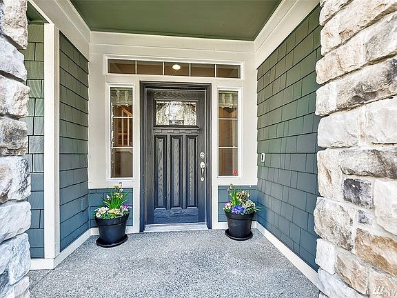 Covered Front Porch Features Natural Stone Accents And Stained Glass Door.