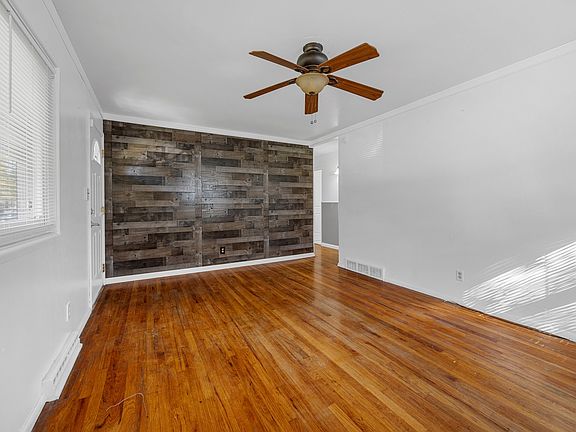 Living room w/ new windows, ceiling fan, coat closet, custom wood accent wall & hardwood floors