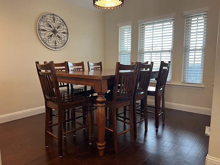Bright formal dining area with large windows and seating for gatherings and entertaining.