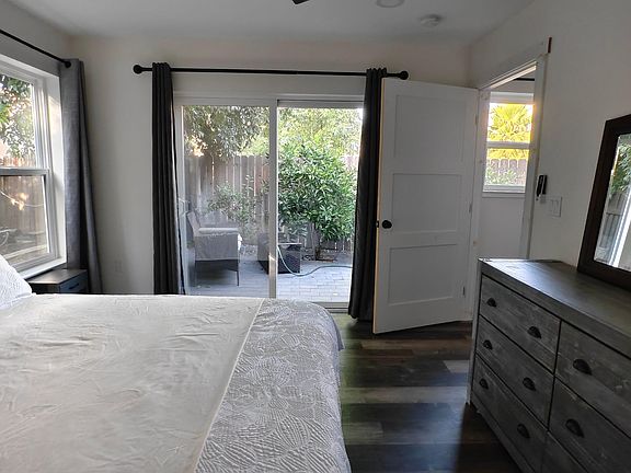Bedroom with a ceiling fan, dresser, and sliding glass door opening to a private patio area with outdoor space.
