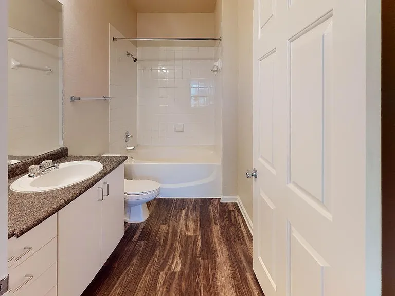 Apartment bathroom with large soaking tub and wood-style flooring.