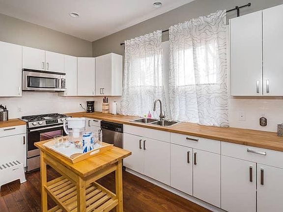 Spacious, L-shaped kitchen with matching stainless steel appliances, solid-wood kitchen island, soft close cabinet doors and drawers, and butcher block counter tops.