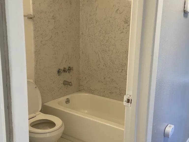 Relax in a full-size tub with granite enclosure and custom tile flooring. Enjoy strong water pressure, spacious layouts, and the quiet charm of a well-maintained older building.
