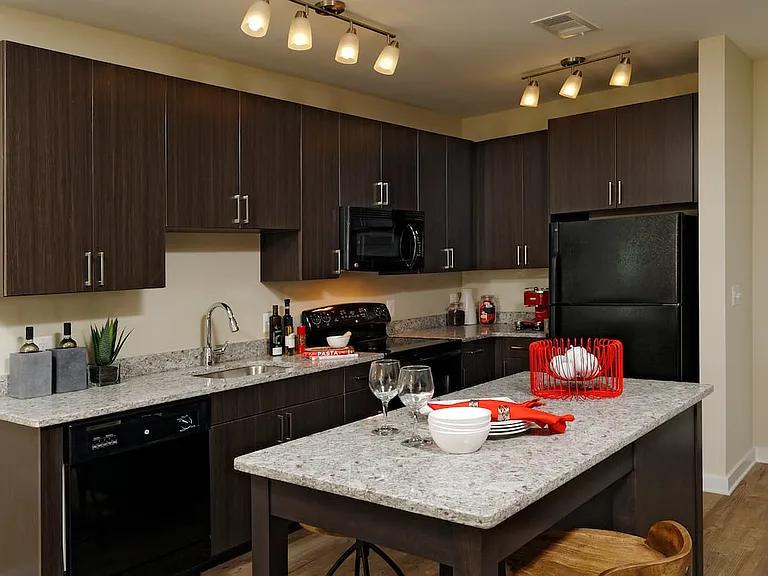 Contemporary kitchen with espresso cabinetry, grey speckled granite countertops, black appliances, and hard surface flooring