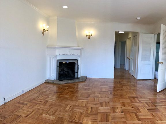 Living room with beautifully detailed wood burning fireplace and hardwood floors and recessed lights
