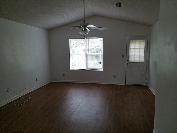 Living / dining room with new vinyl plank flooring and vaulted ceiling and rear entry to back patio.