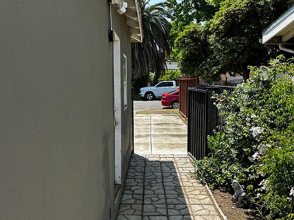 Side. 
Green. Paved. Strong LED floodlights all around the house. Extra security.