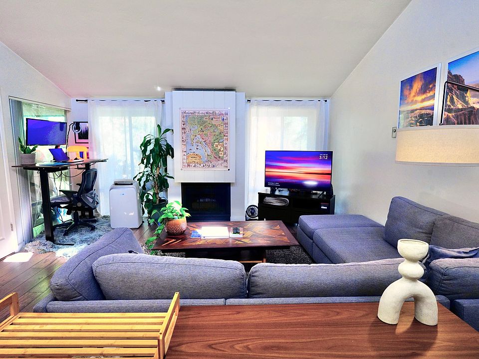 Living room with desk+monitor, TV, XL couch, floor-to-ceiling windows, skylights, wall art