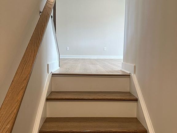 Hardwood staircase leading up to first floor with Luxury Vinyl Plank flooring throughout