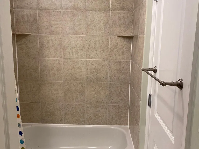 Full shower and tub combo! Towel rods conveniently mounted to back of door leading to hallway.
