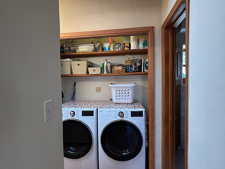 View down short hallway towards washer and drier with door to bathroom on the left.