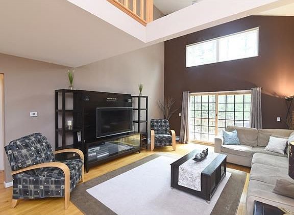 Spacious living room with custom windows and cathedral ceilings. Sliding glass door leads to over si