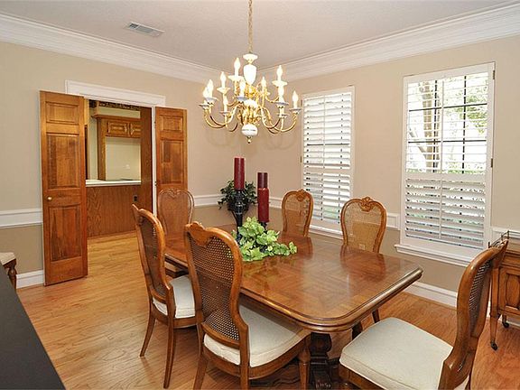 The dining room is a large room. It has chair rails, crown moldings, wood flooring, and windows with