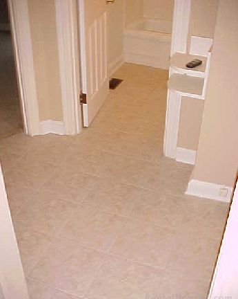 Hallway with new tile floor between first floor bedroom, full bath, living/dining rooms, and kitchen