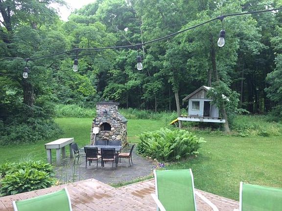 Outdoor living space with treehouse, patio, and pizza oven.