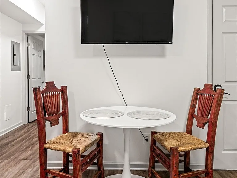 Two-seat dining nook with a round table, rustic chairs, and a wall-mounted TV, set on durable wood-look flooring.