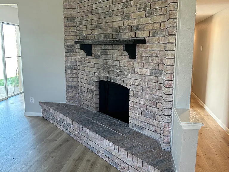 Fireplace in living area with access to hall and kitchen.