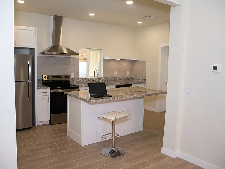Open kitchen space leading to living room with brand new stainless steel appliances and huge kitchen island.