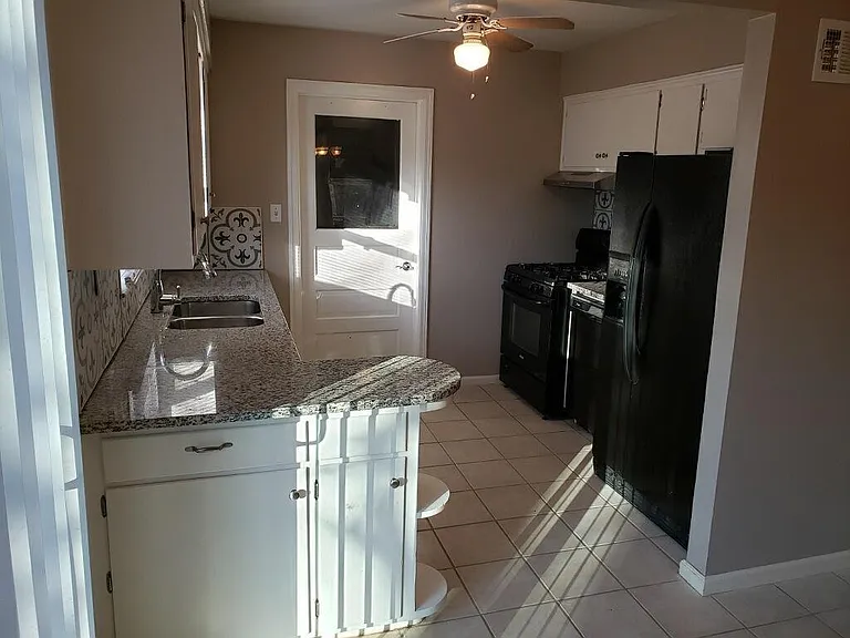 Gas stove, dishwasher and fridge. Door leads to laundry room and screened in porch.
