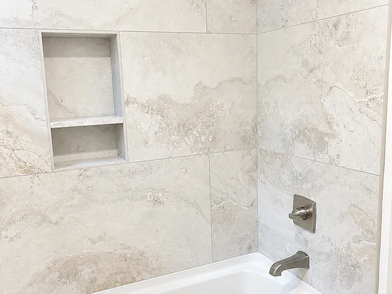 The bathroom is an elegant retreat where you can unwind in the deep soaking tub/shower combination, complemented by stylish, modern tile for a sophisticated, spa-like atmosphere.