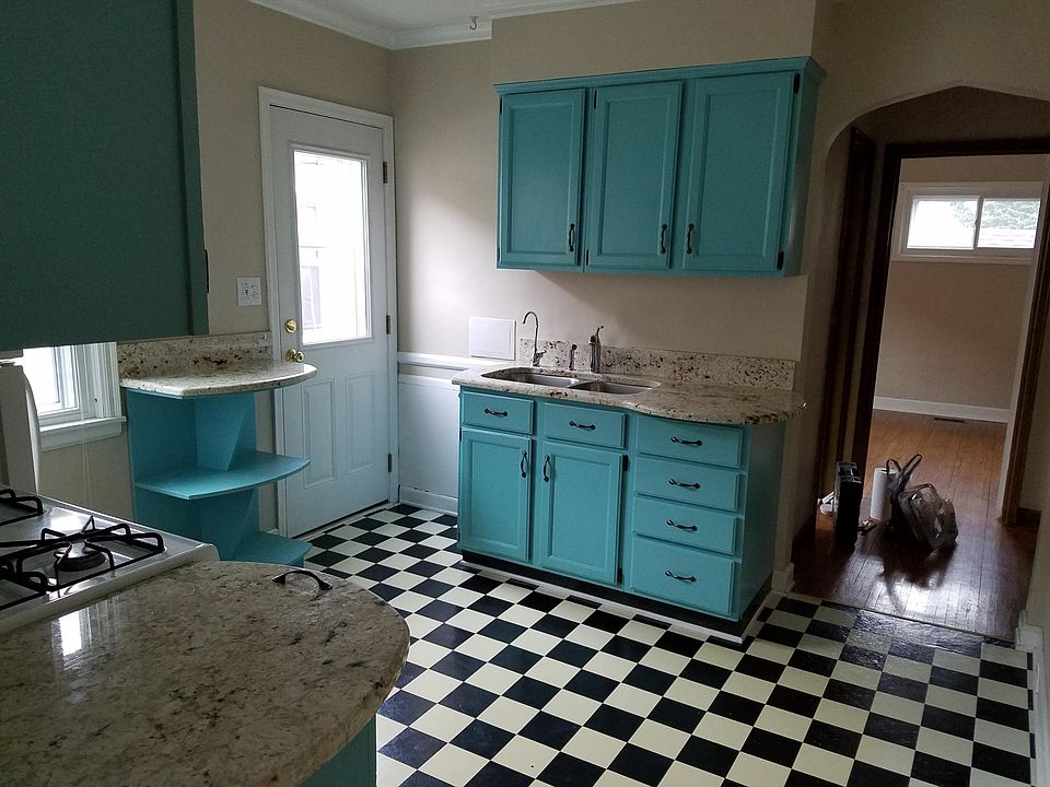 Kitchen with side entrance leading to backyard. Hallway ahead with closet to the right and stairway leading upstairs. On the left is the bathroom and bedroom straight ahead.