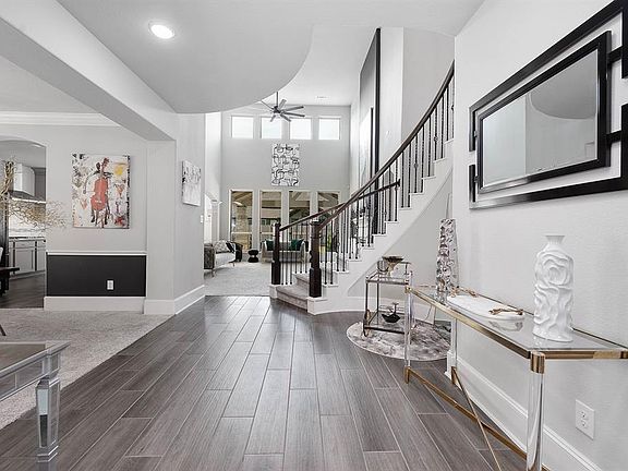 This shot leads us deeper into the home, showcasing the aesthetic design and immaculate floor plan of this home. Wood tile floor and plush carpet meet in perfect contrast. Large windows paired with gorgeous fixtures and recessed lighting keep this ho