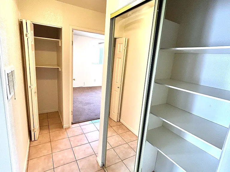 hall with two storage closets and mirrored door.