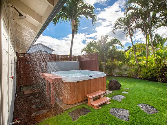Outdoor shower, jacuzzi, privacy trellis and stepping stones leading towards storage shed.