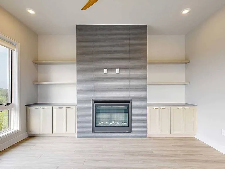 The Wrangler Penthouse living room blends warmth and elegance with a modern fireplace, custom shelving, and designer touches throughout.
