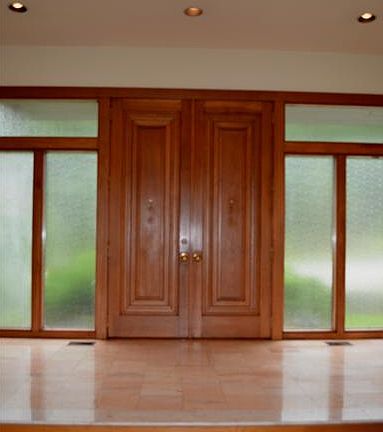 Huge wood double doors to marble tile foyer