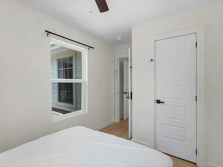 Well-proportioned bedroom with a large window, ceiling fan, and convenient closet access for everyday storage.