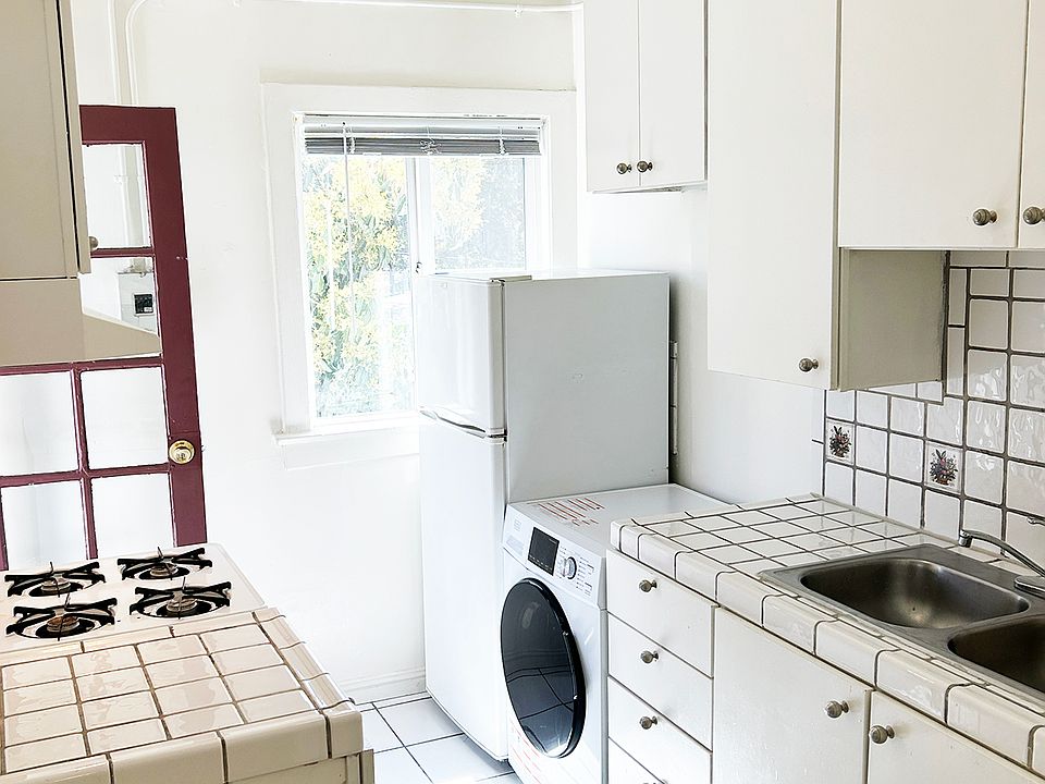Kitchen from hallway with back door open, washer/dryer, refrigerator, stove/oven and hood.