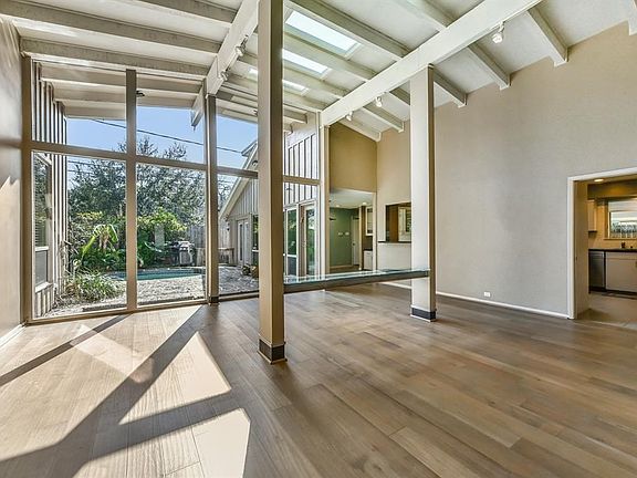 Soaring ceilings create a marvelous open floorplan with walls of windows overlooking the pool area.
