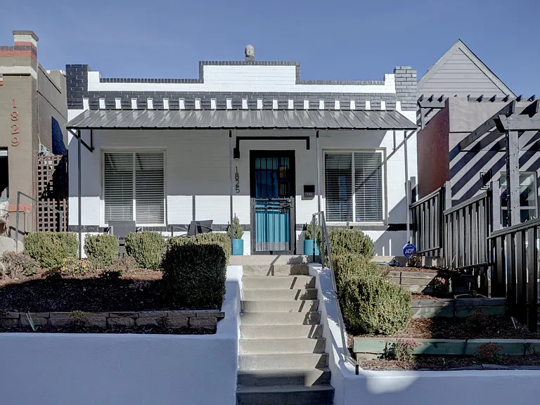 Front of house with patio chairs and table.